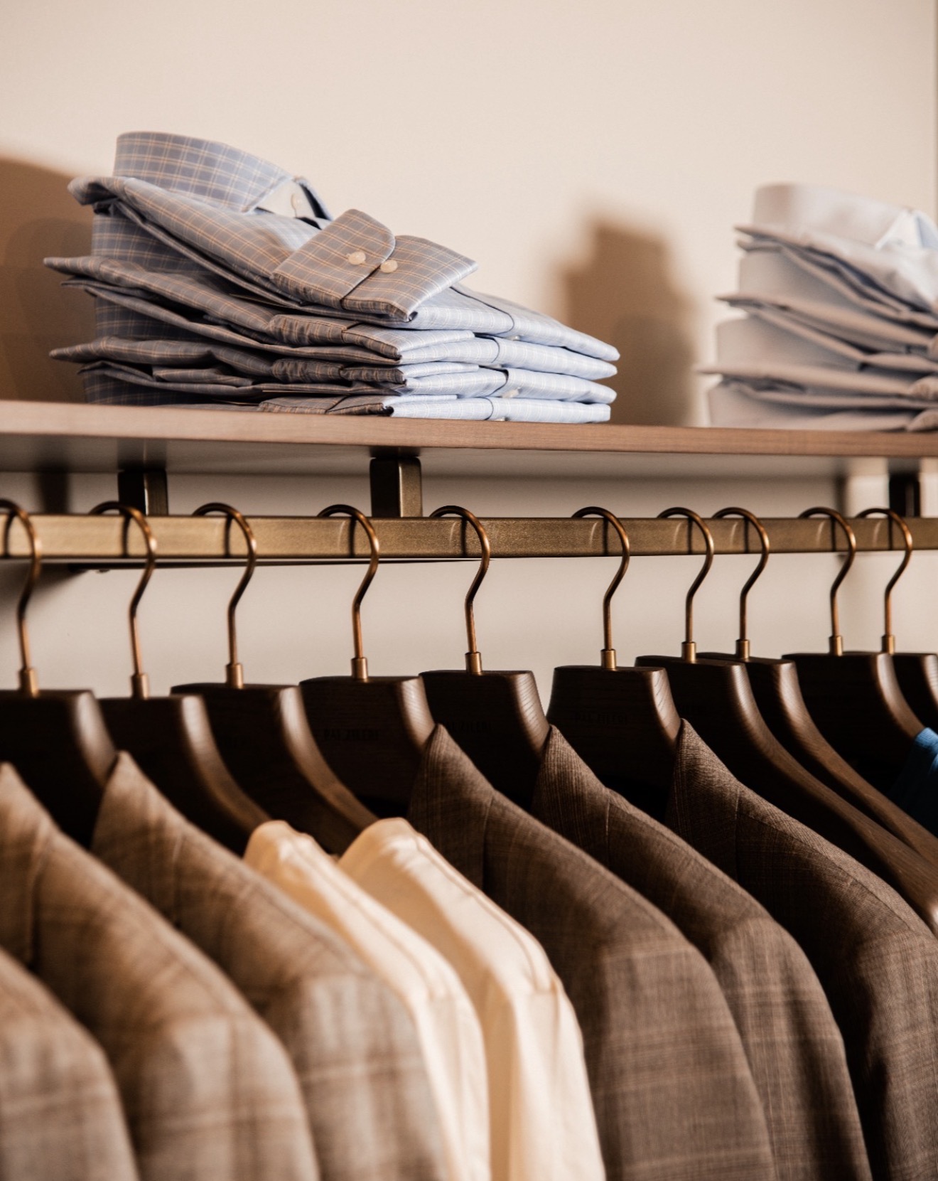 Folded shirts and tailored jackets on wooden hangers inside a Pal Zileri boutique