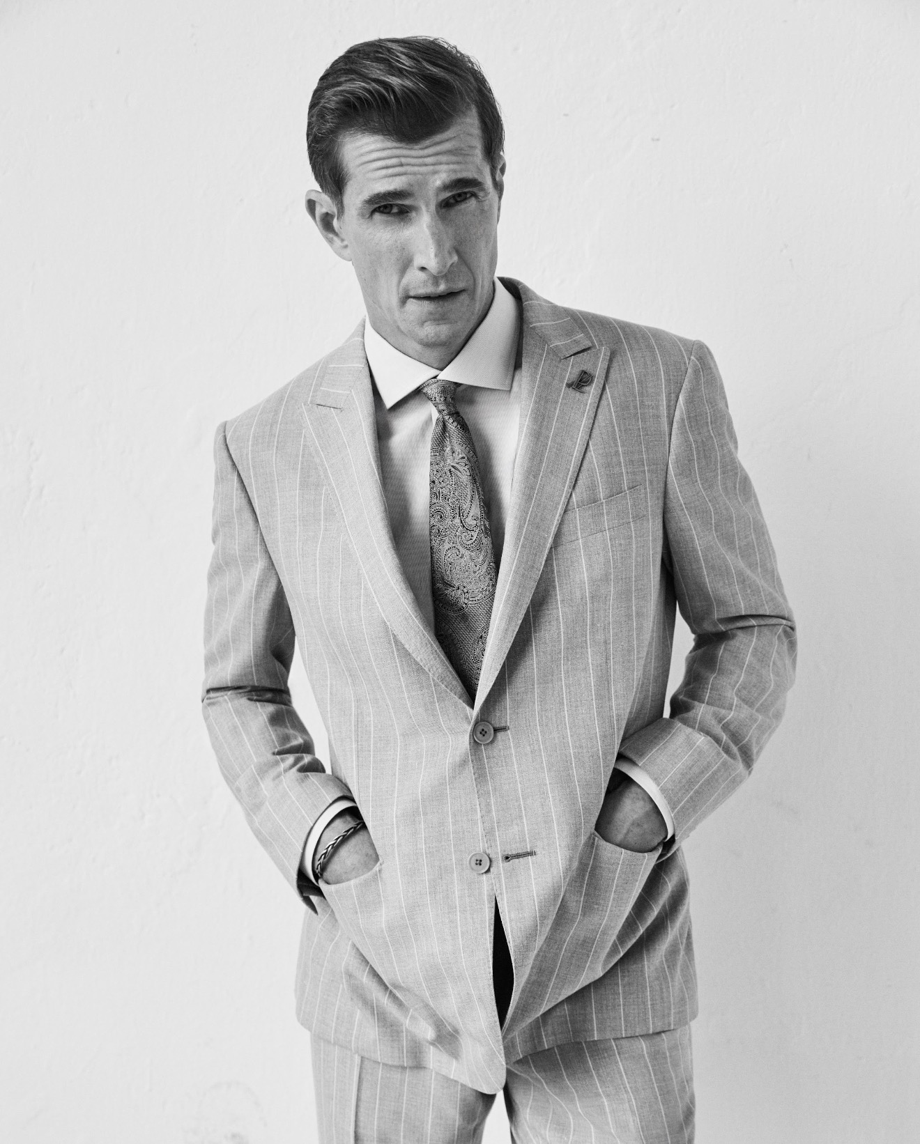 Man in a pale pinstripe Pal Zileri suit, hands in pockets, black and white portrait